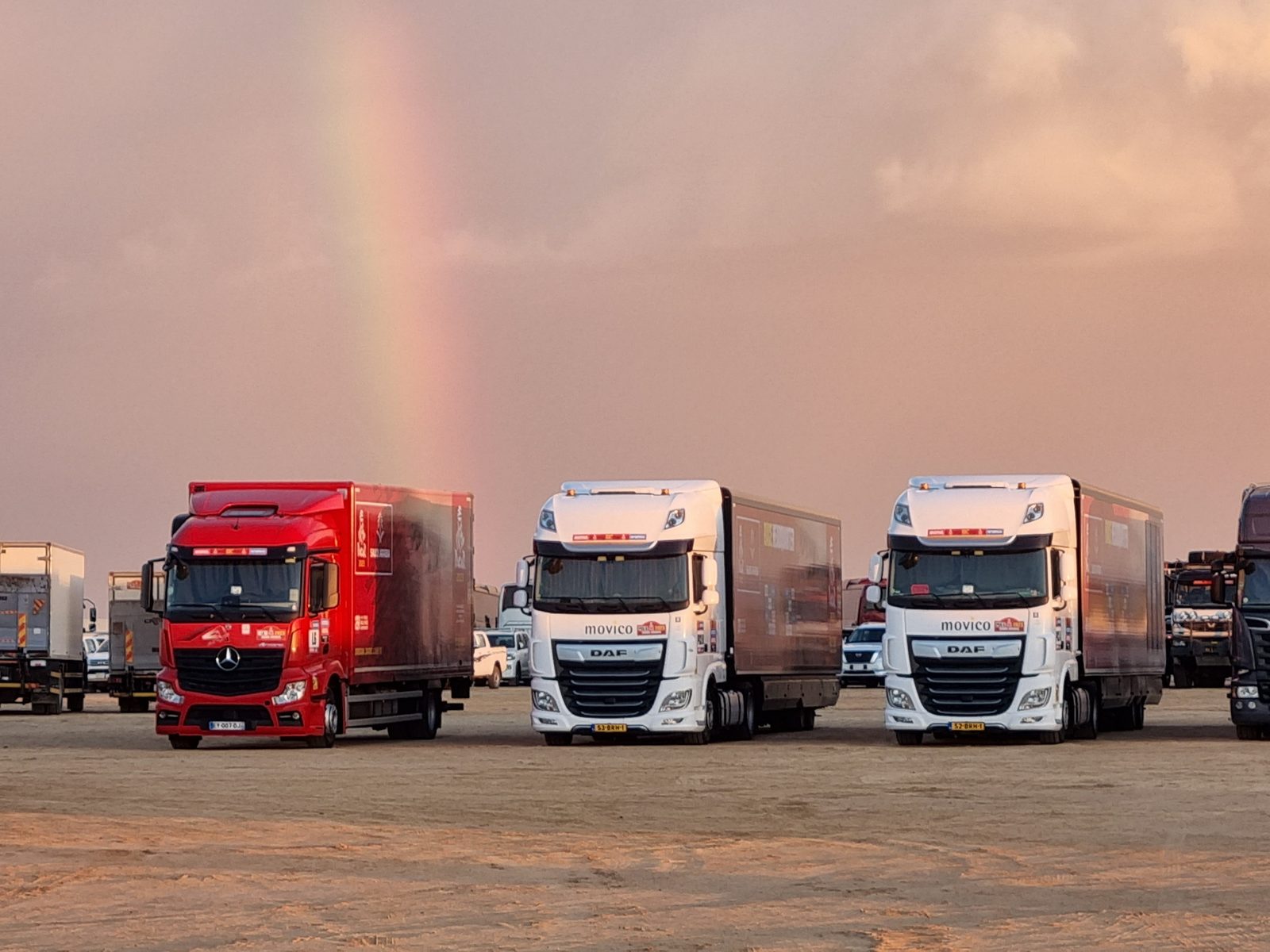 Lkw im Biwak der Rallye Dakar unter einem Regenbogen